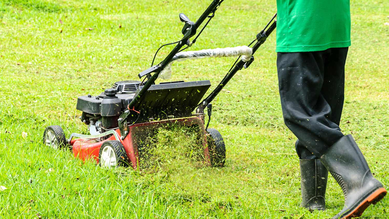 Worker mowing grass with mowing machine