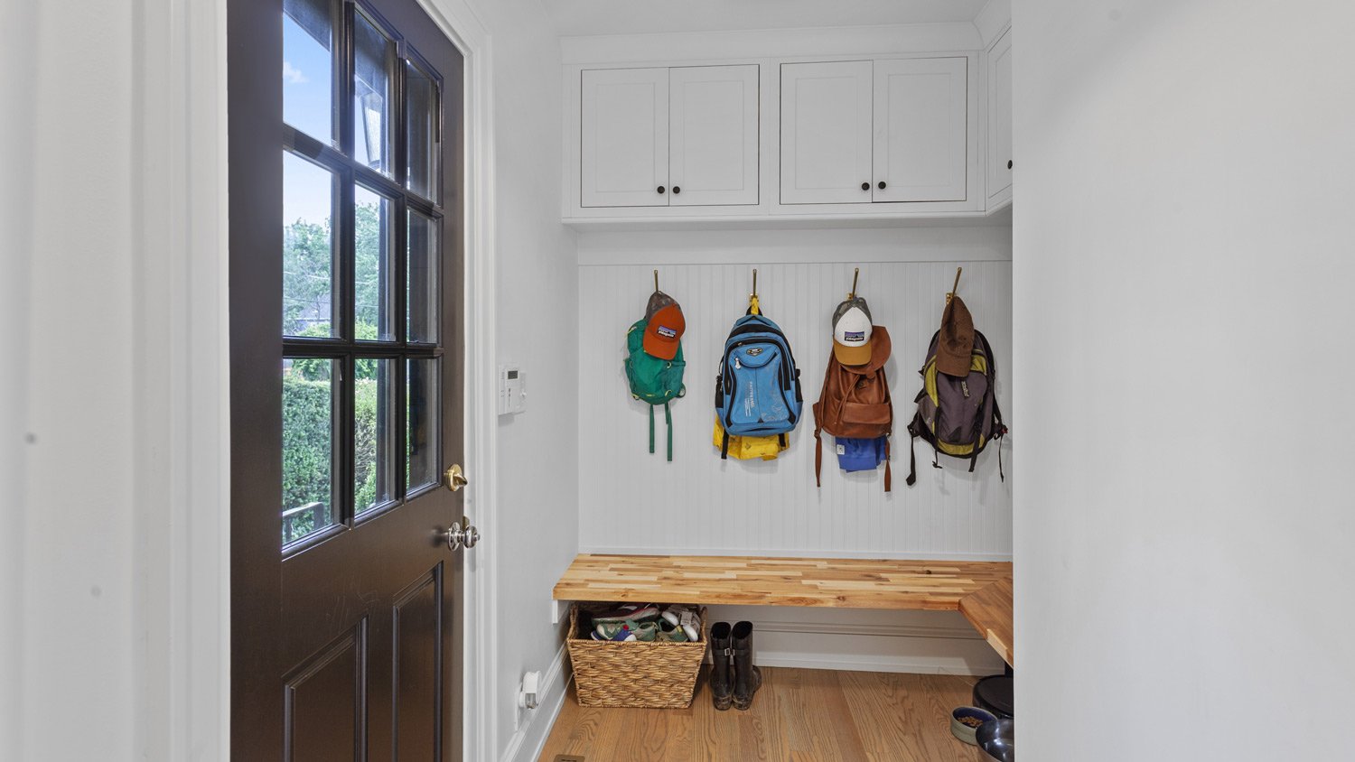 A mudroom with backpacks hanging and shoes