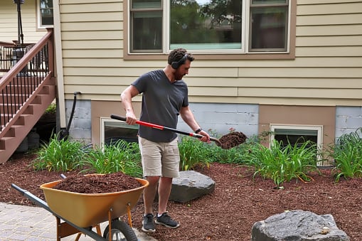 Man mulching a flower bed in the yard