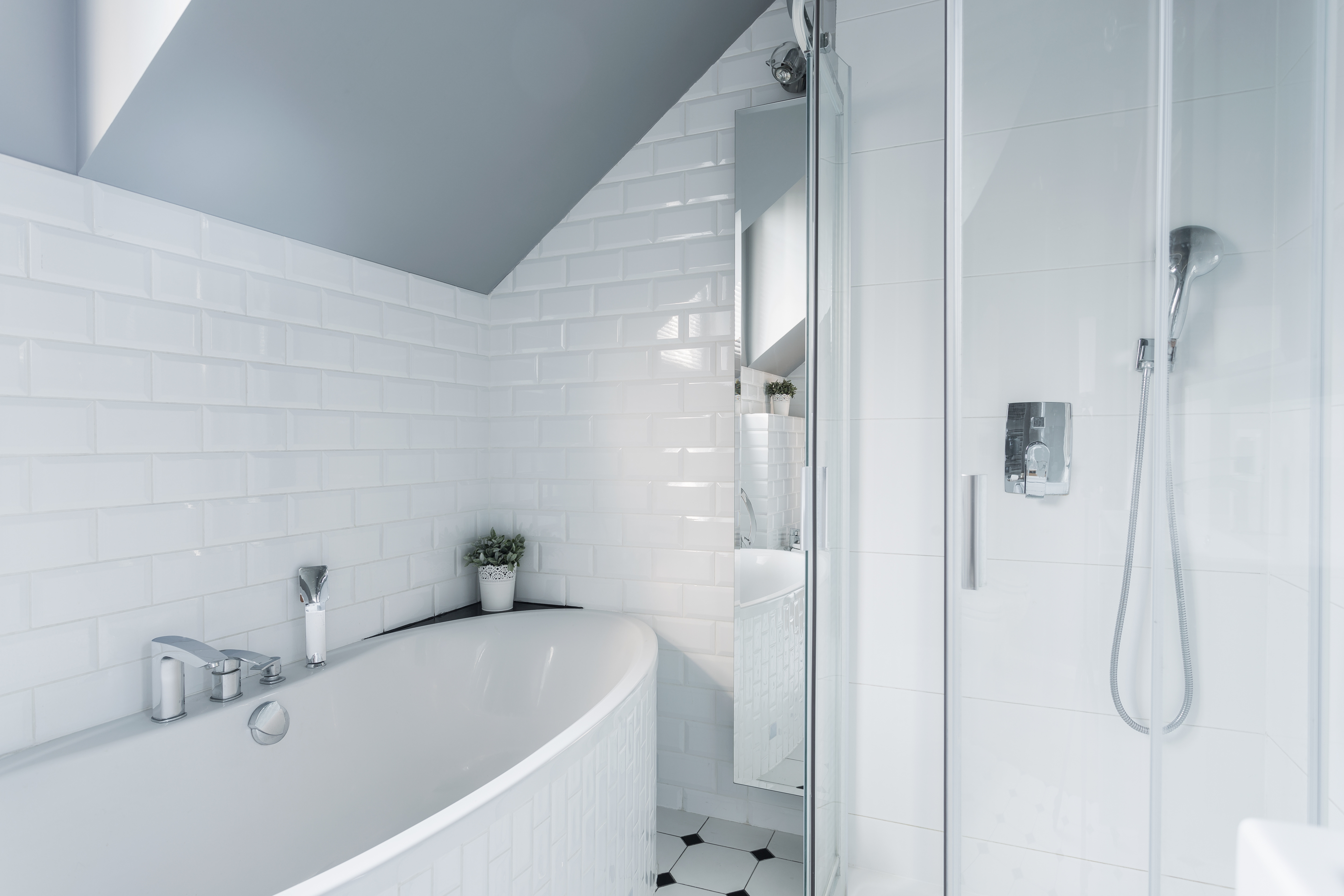 Separate bathtub and shower in white-tile bathroom