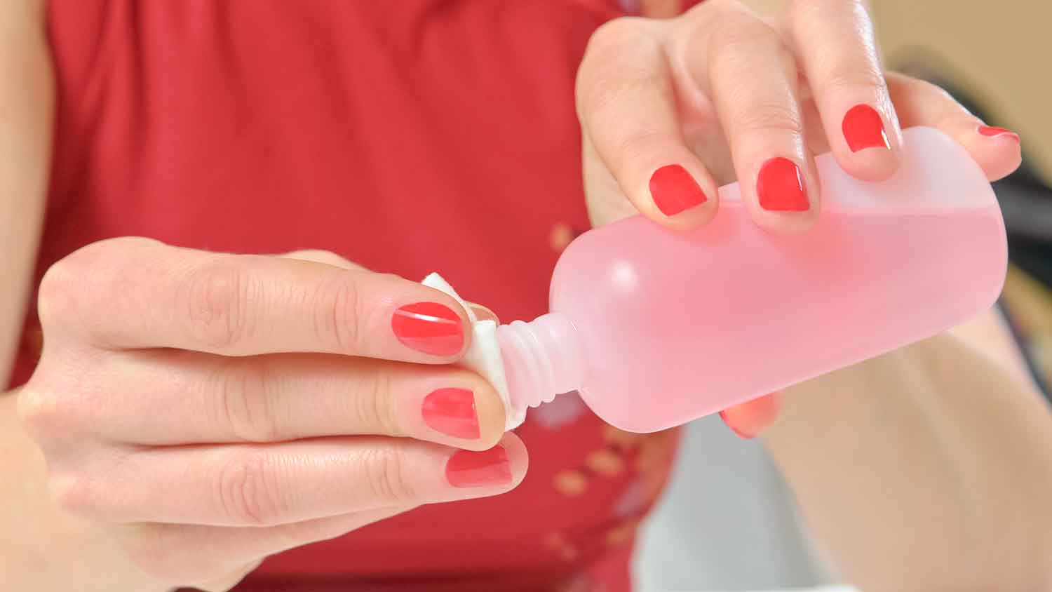 Woman wetting cotton pad with nail polish remover