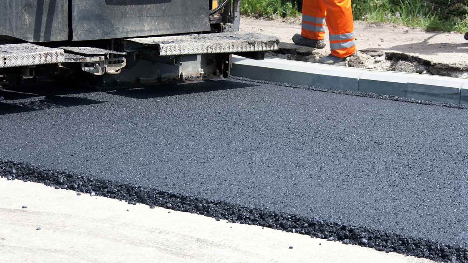 Machine leveling a new asphalt road