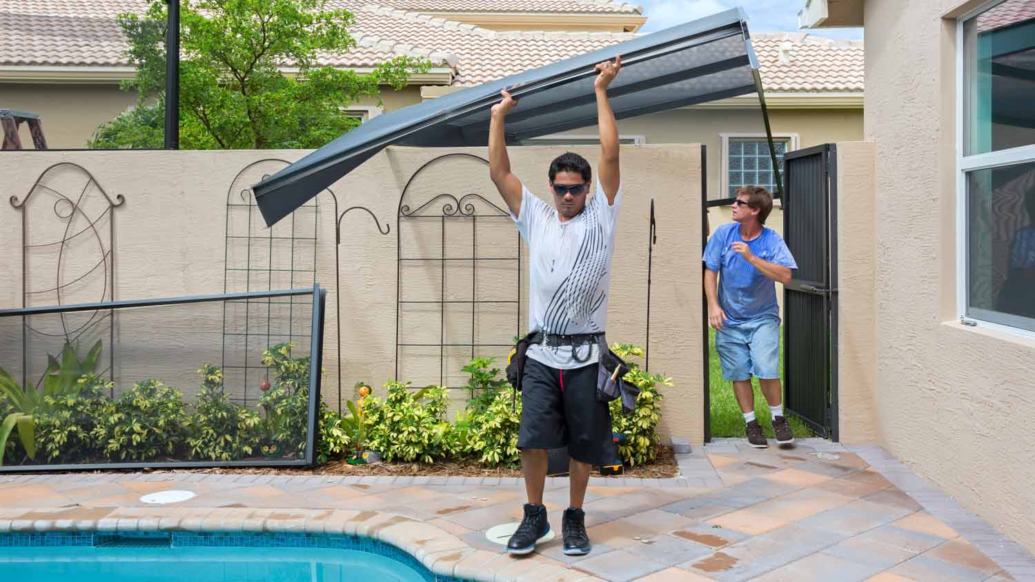 man carrying mesh screen for pool enclosure