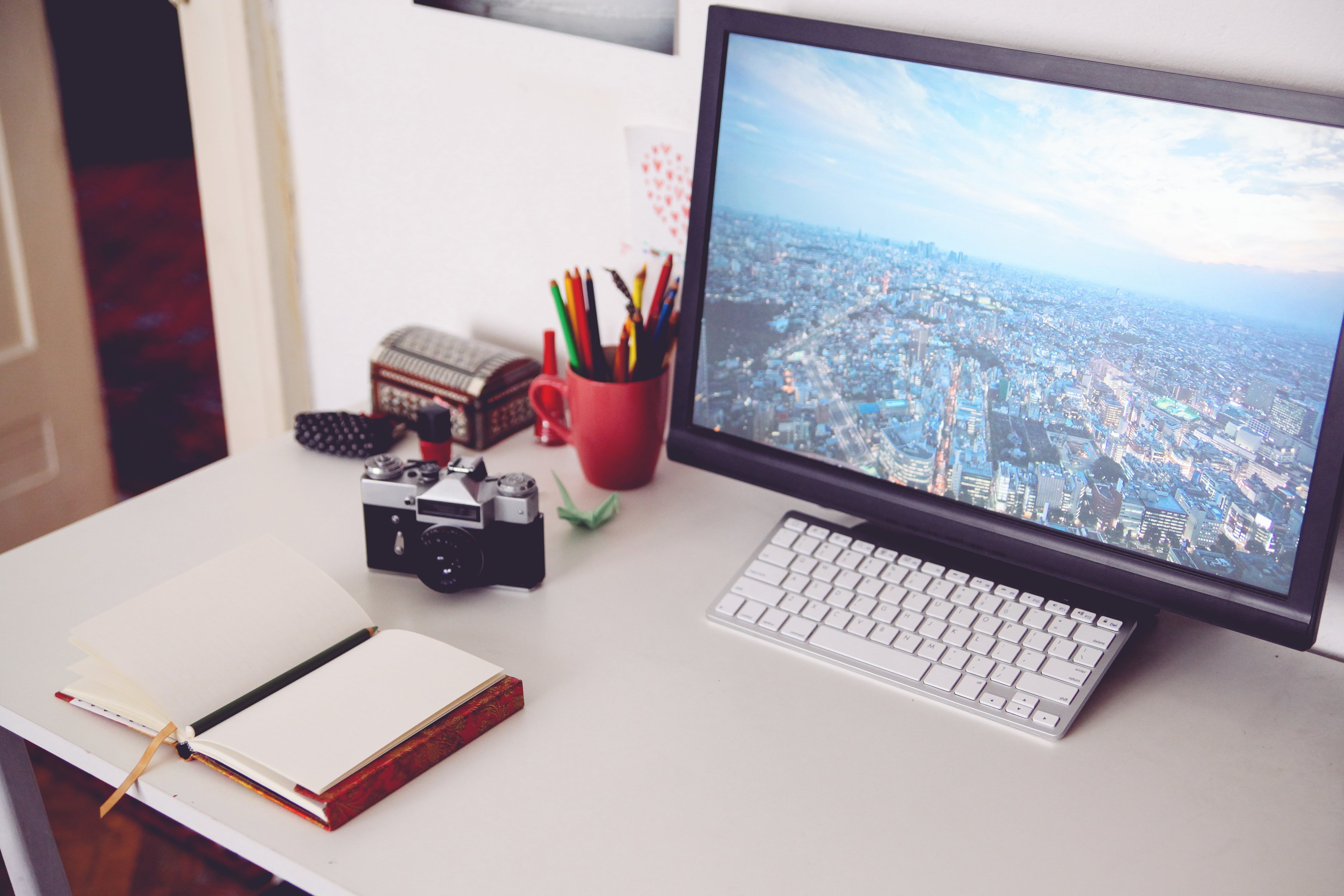 Home office desk with computer, keyboard, journal, and camera