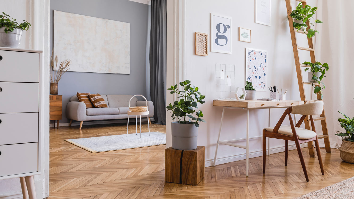 An office space with wooden floors and a living room in the background