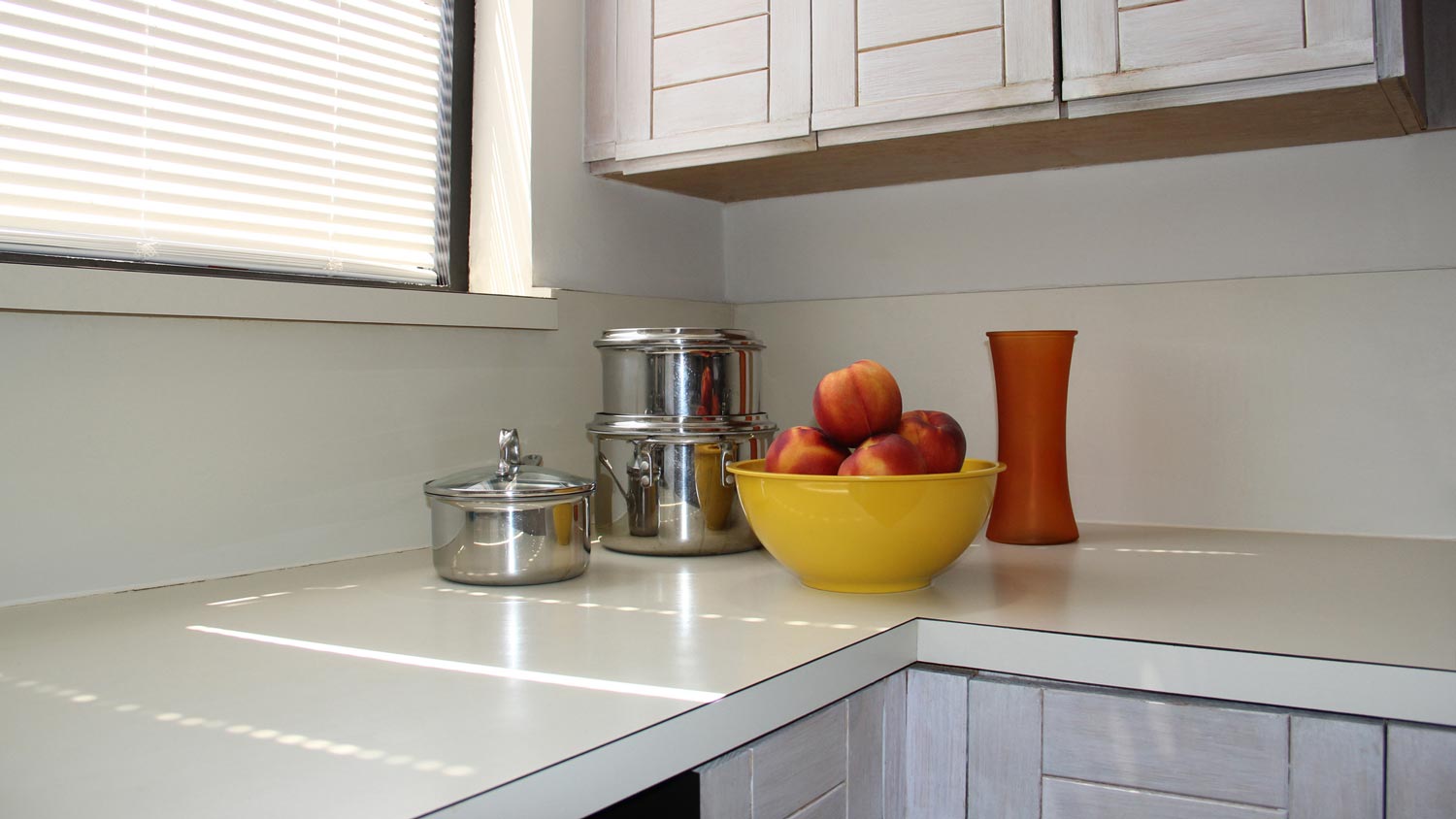 An old laminate countertop with a bowl of peaches on top of it