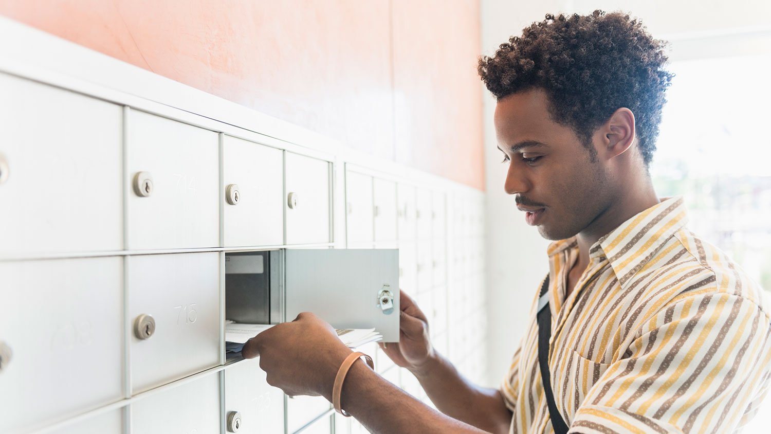 Man opening individual mailbox slot