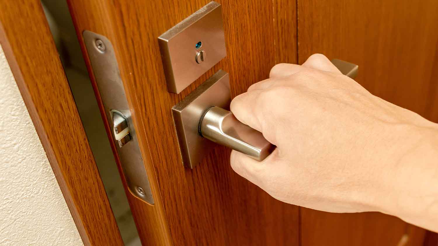 Hand turning doorknob to open the door