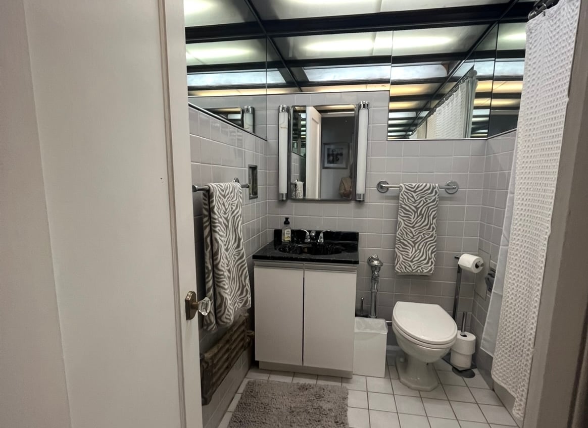 Outdated bathroom with dull floor tiles and fluorescent ceiling lights