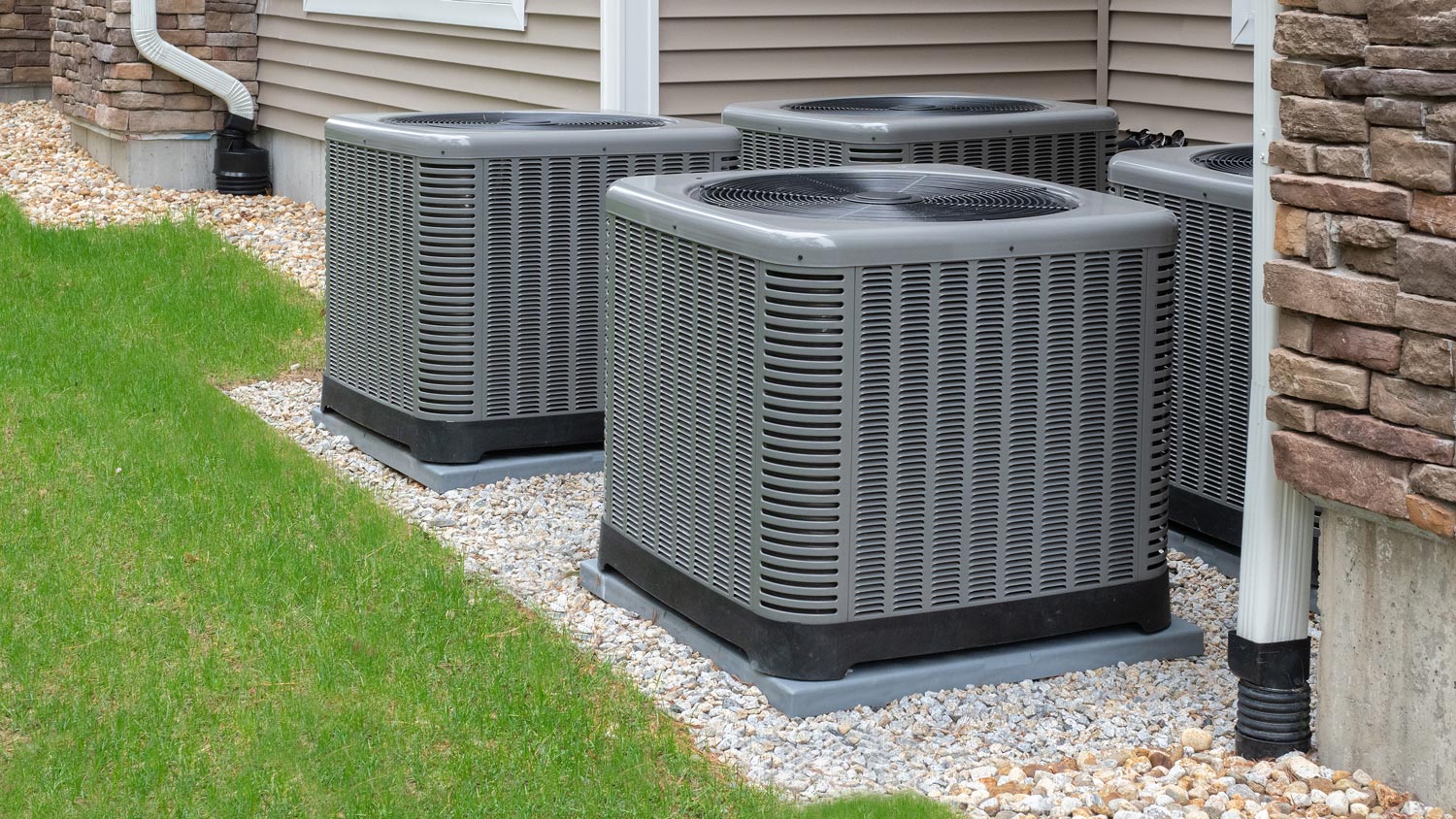 Four outdoor air-conditioning and heating units in a backyard