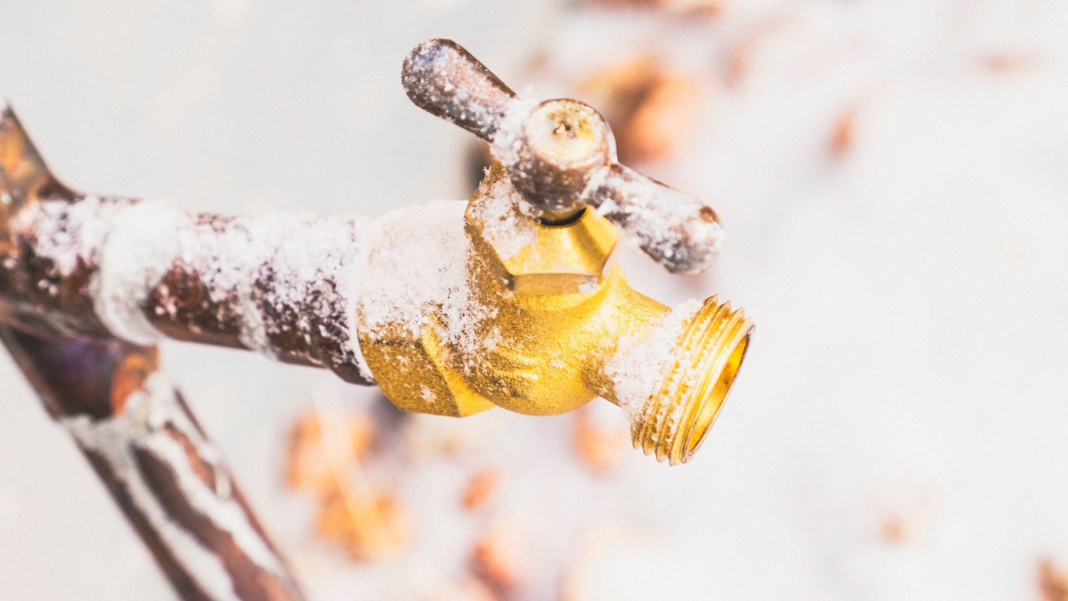 Frozen outdoor water faucet covered in snowflakes