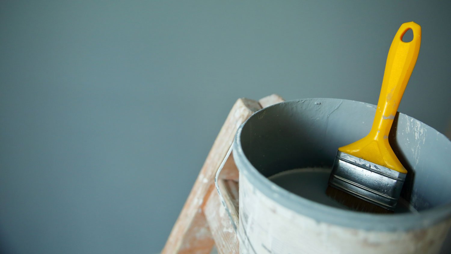 Close-up of a paint bucket with a paintbrush dipped in