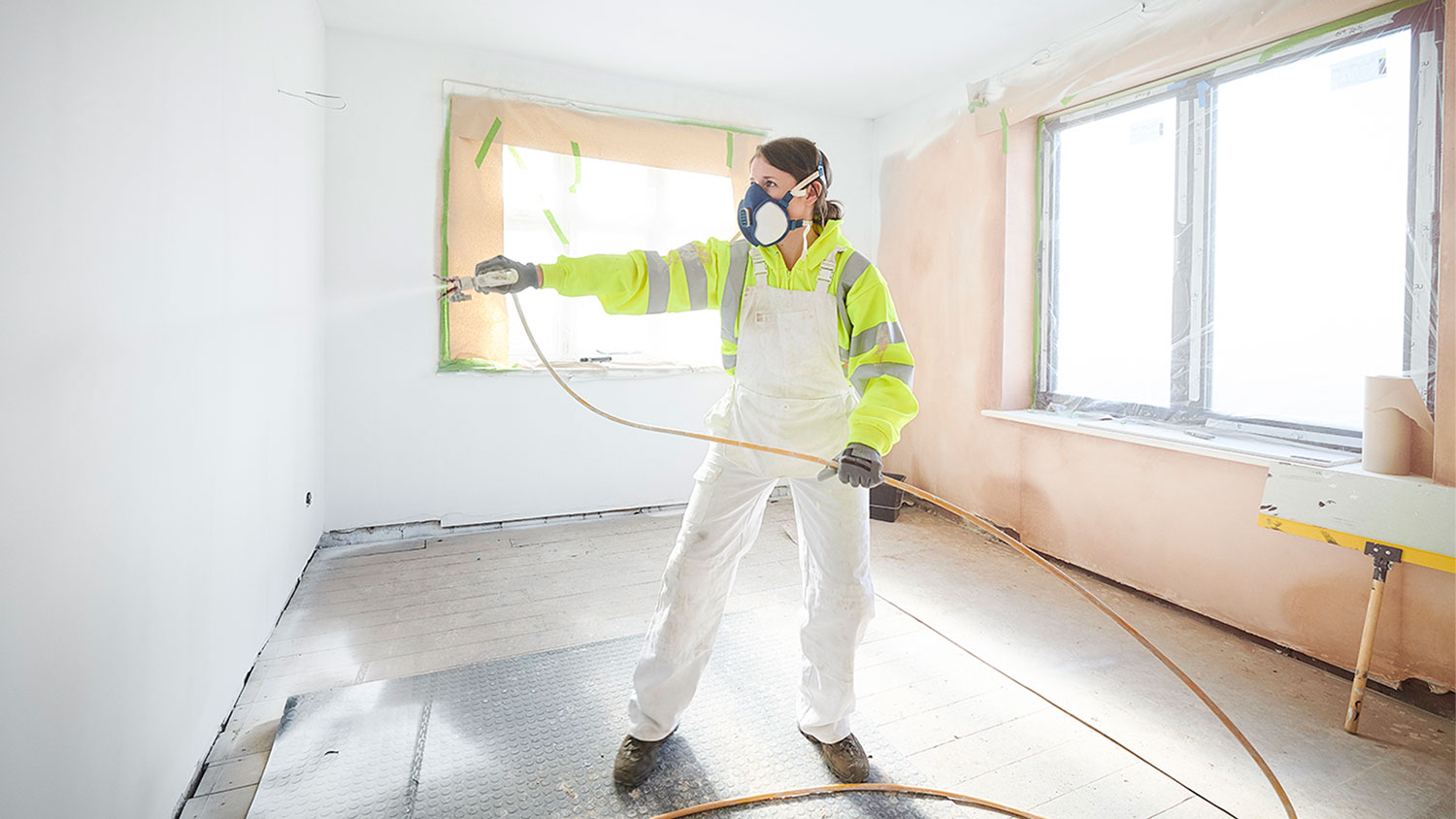  woman painting room with spray gun