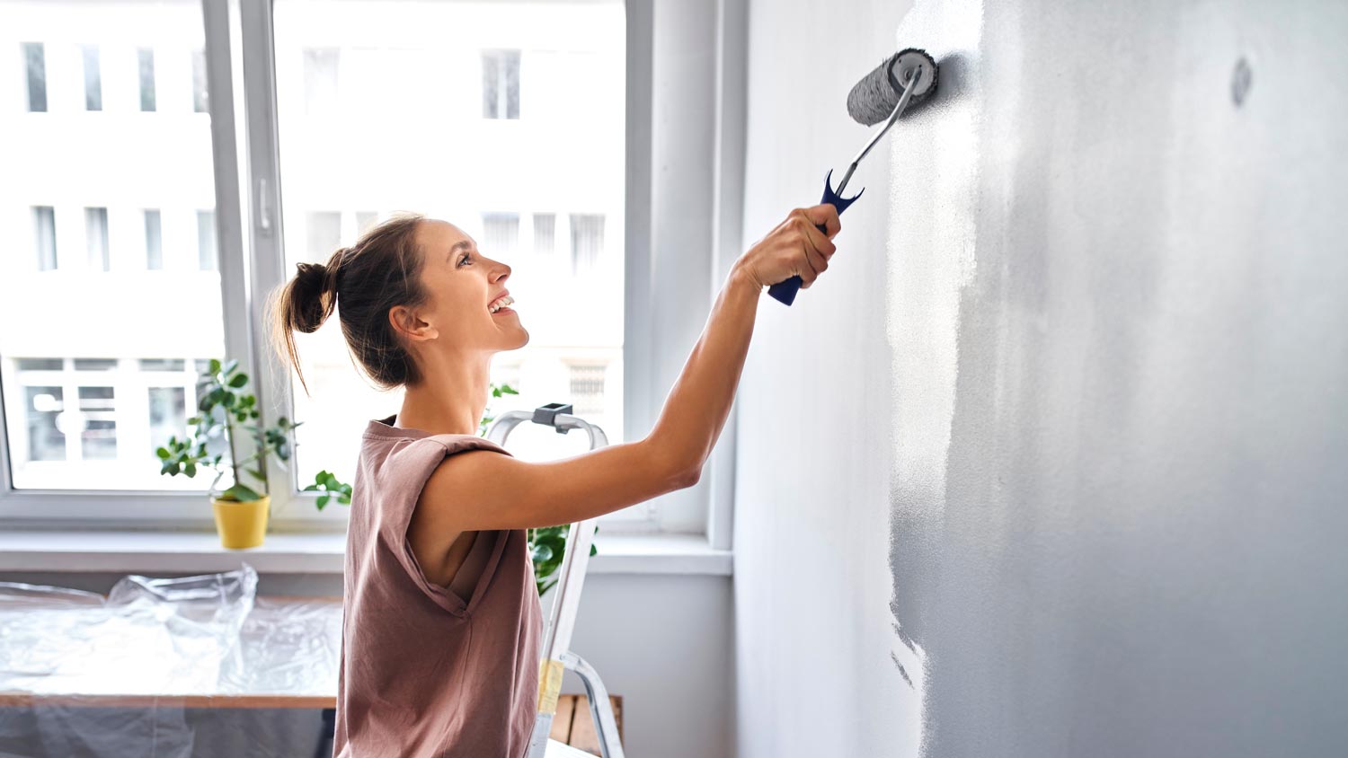 woman painting wall gray