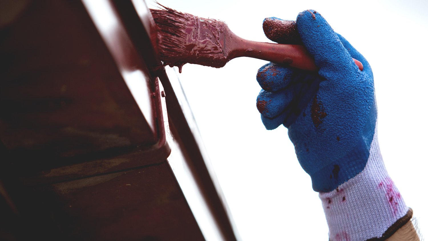 Construction work with a brush painting the gutter