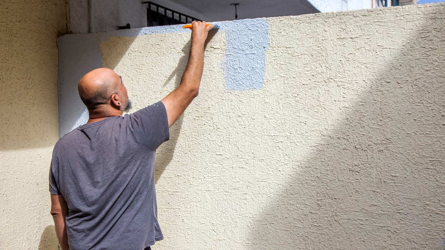 Man painting textured wall