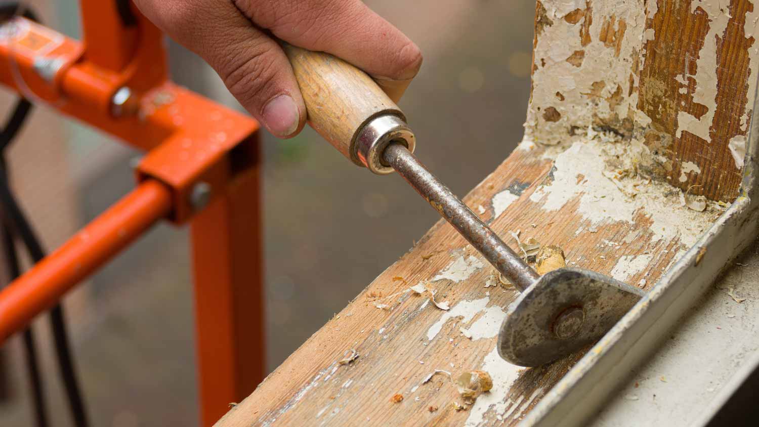 A painter removing old paint with a scraper