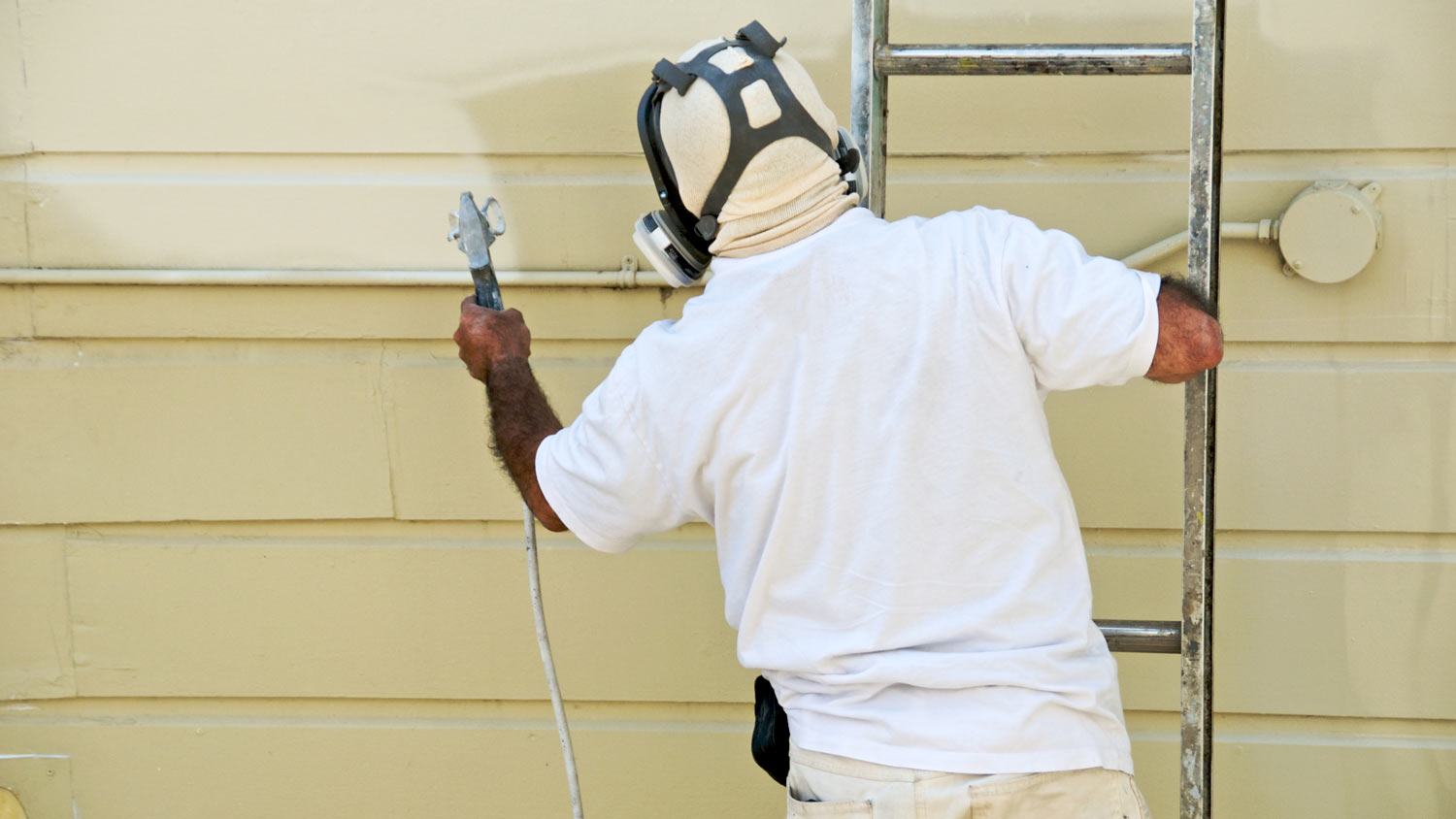 man painting aluminum siding