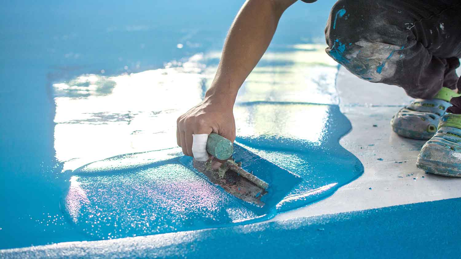 Worker painting garage floor with epoxy 