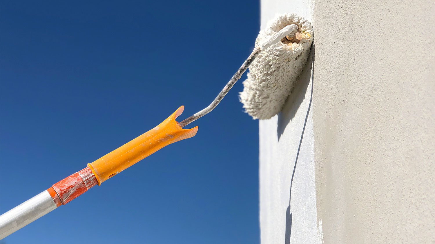 A view of a stucco exterior wall being painted