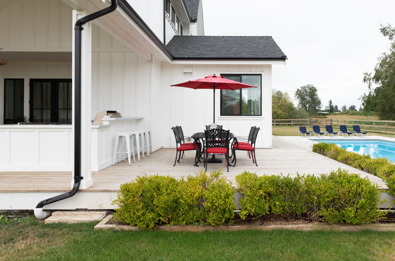 Patio on the back of a modern farmhouse by the pool