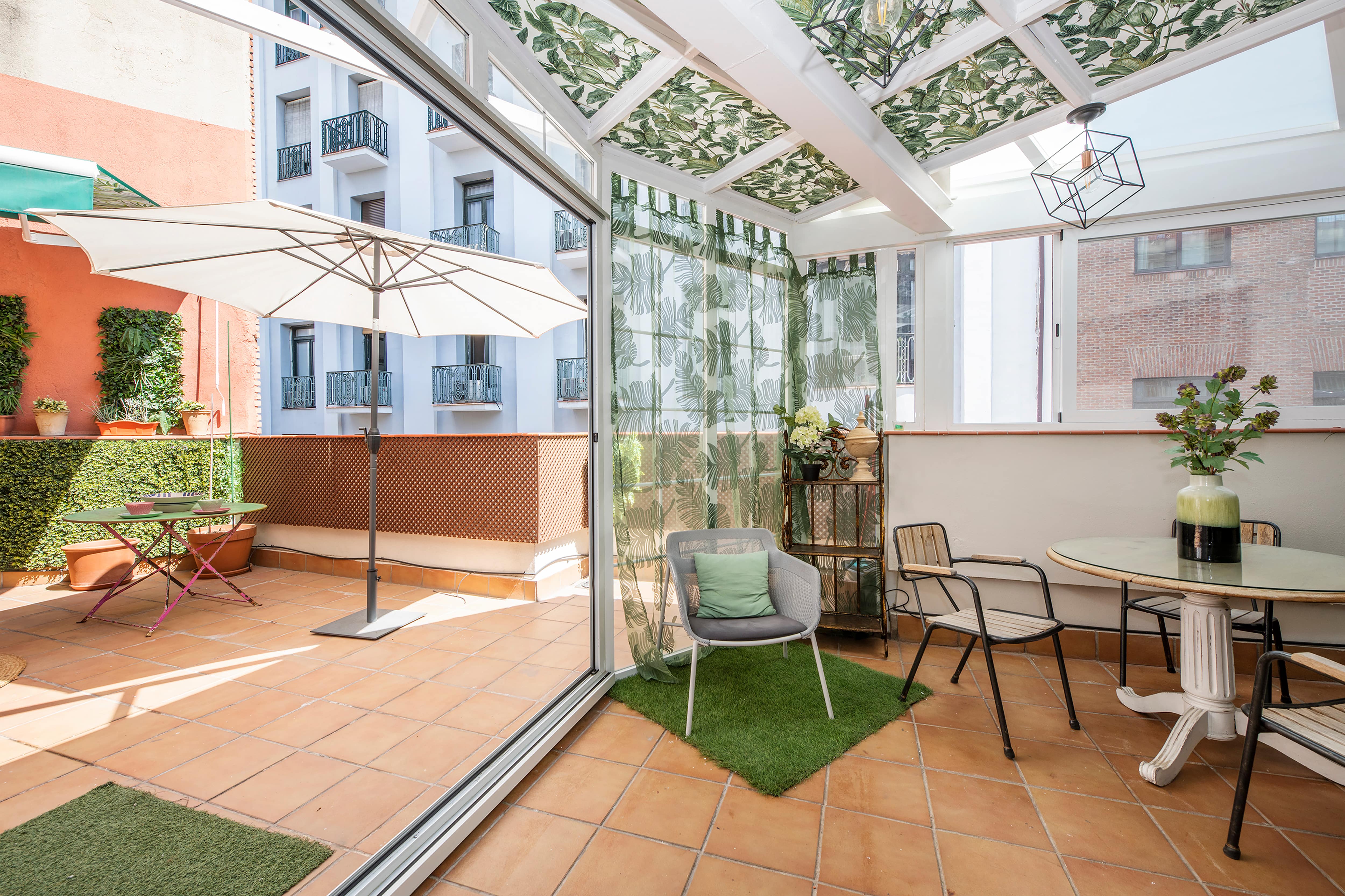 An enclosed outdoor patio with a dining table, seating, and several plants 