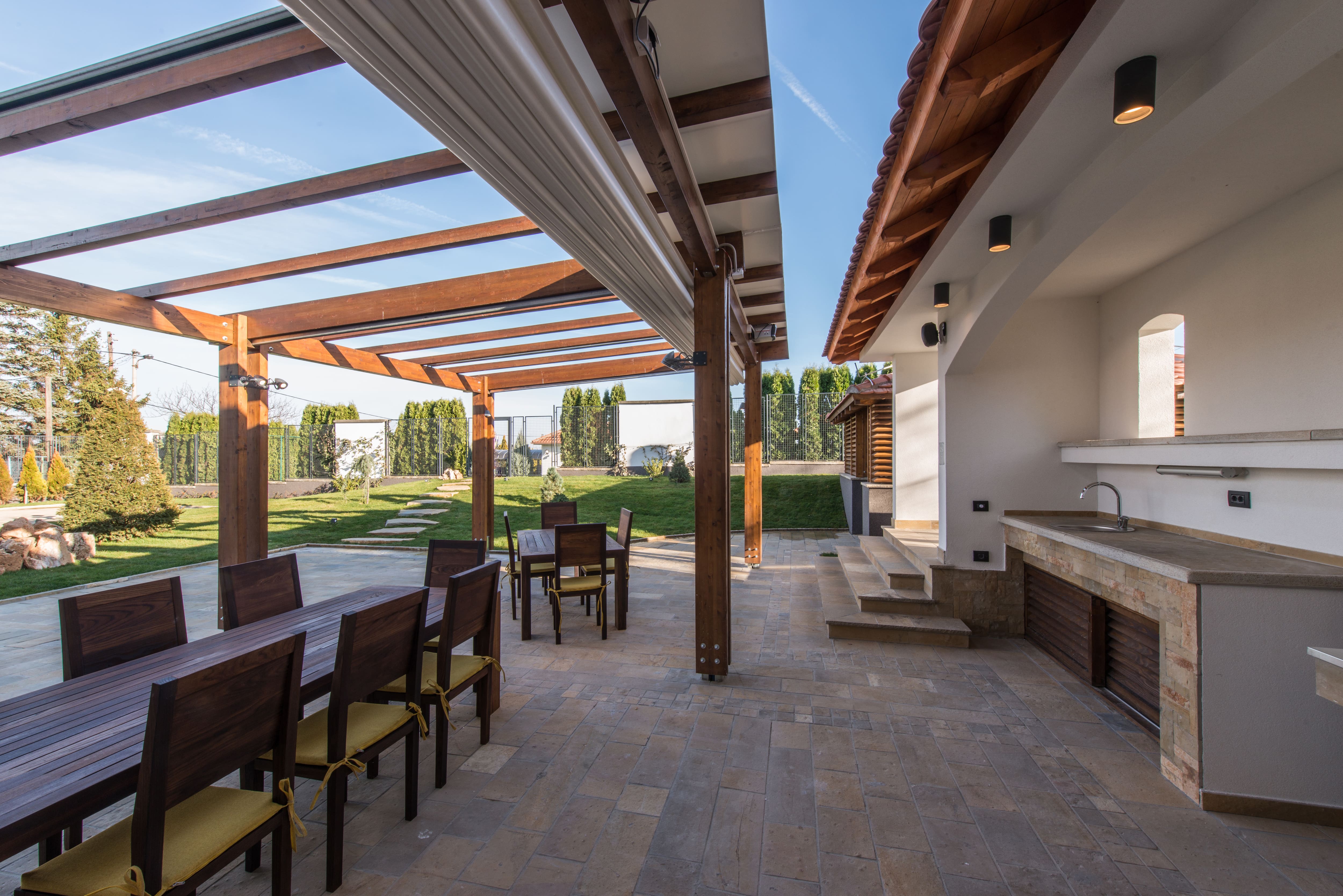 A terrace with a long wooden table under a pergola