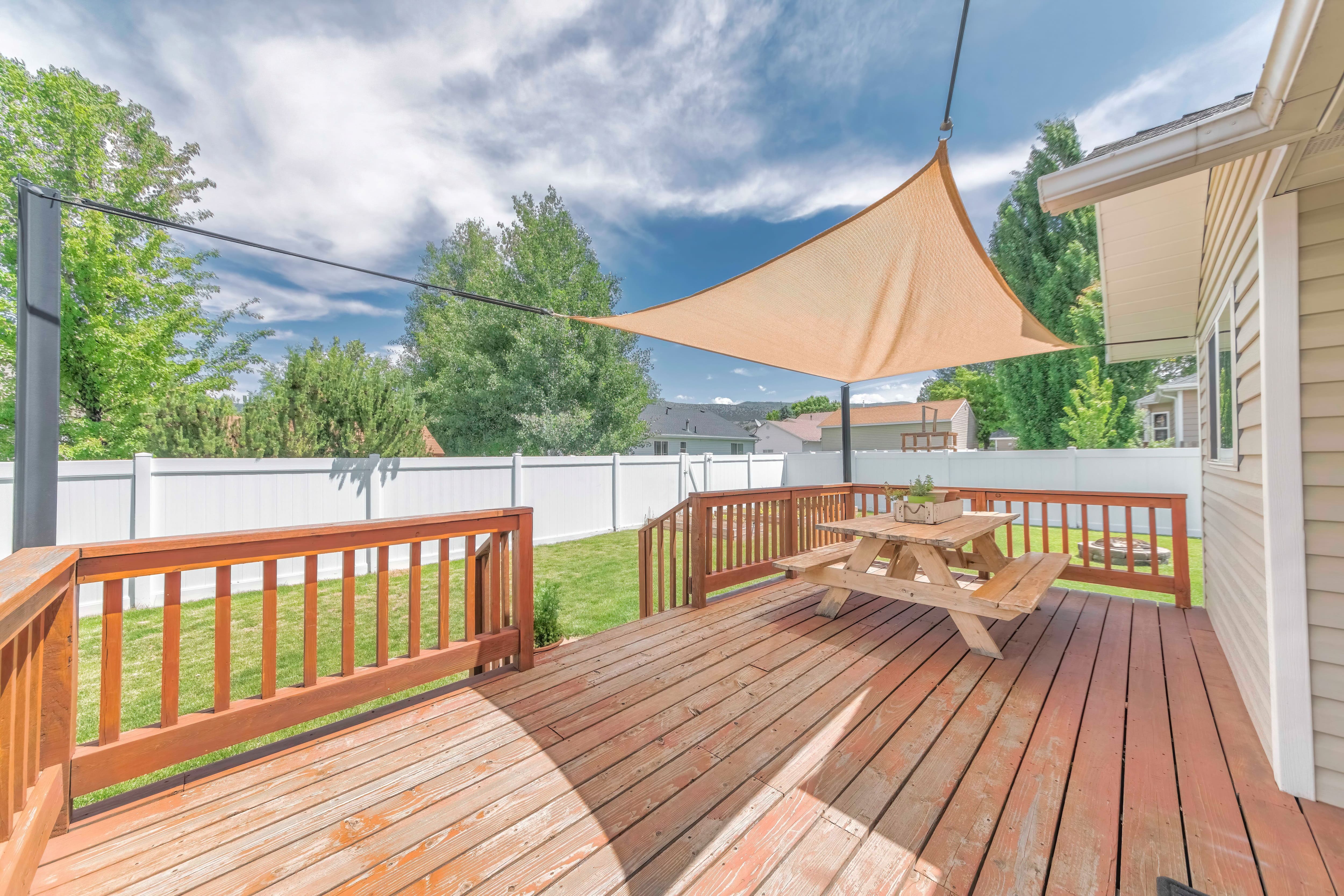 A wooden patio with picnic table and a simple vinyl cover