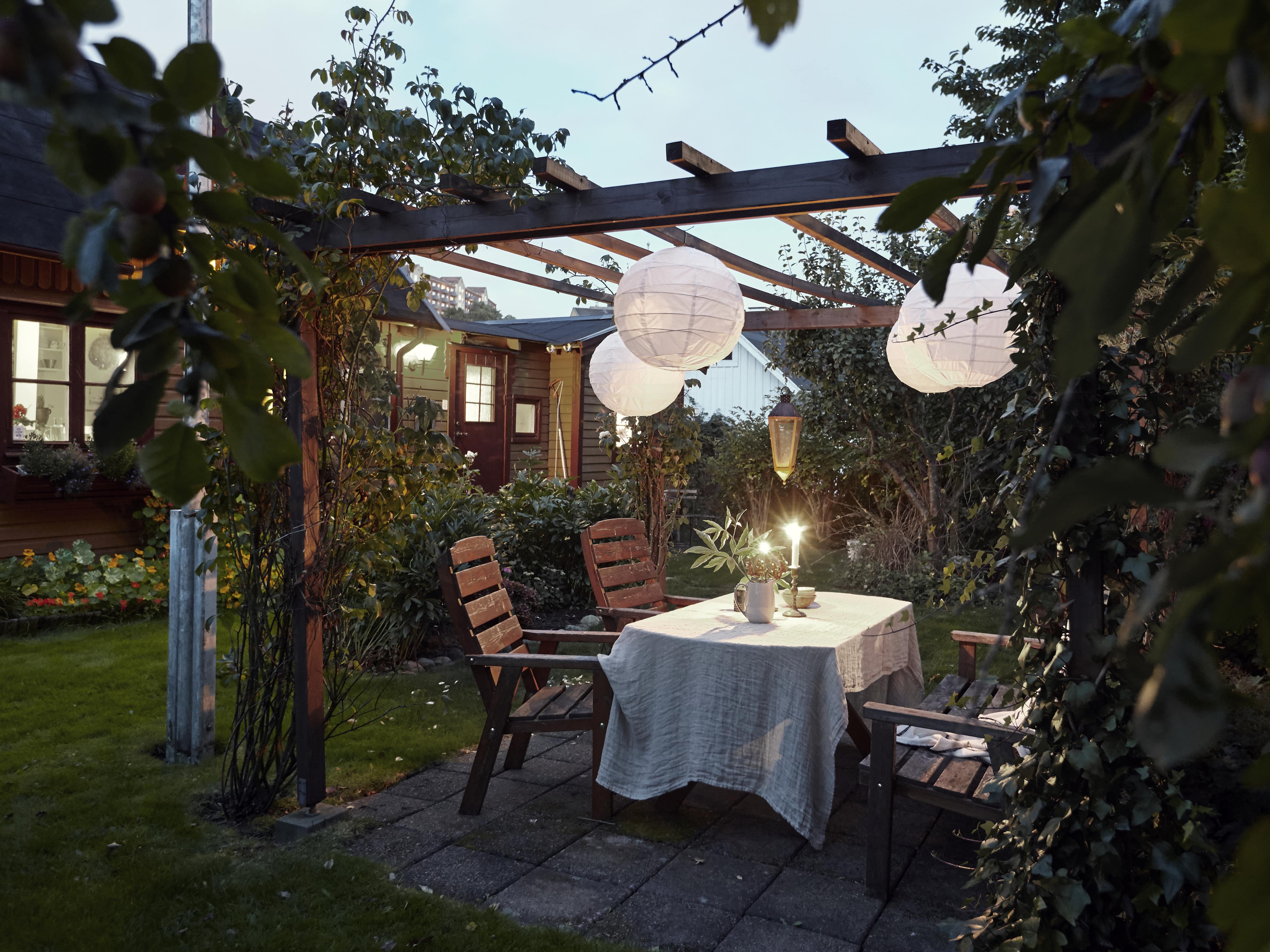 A trellis patio cover with climbing vines and paper lantern pendant lights