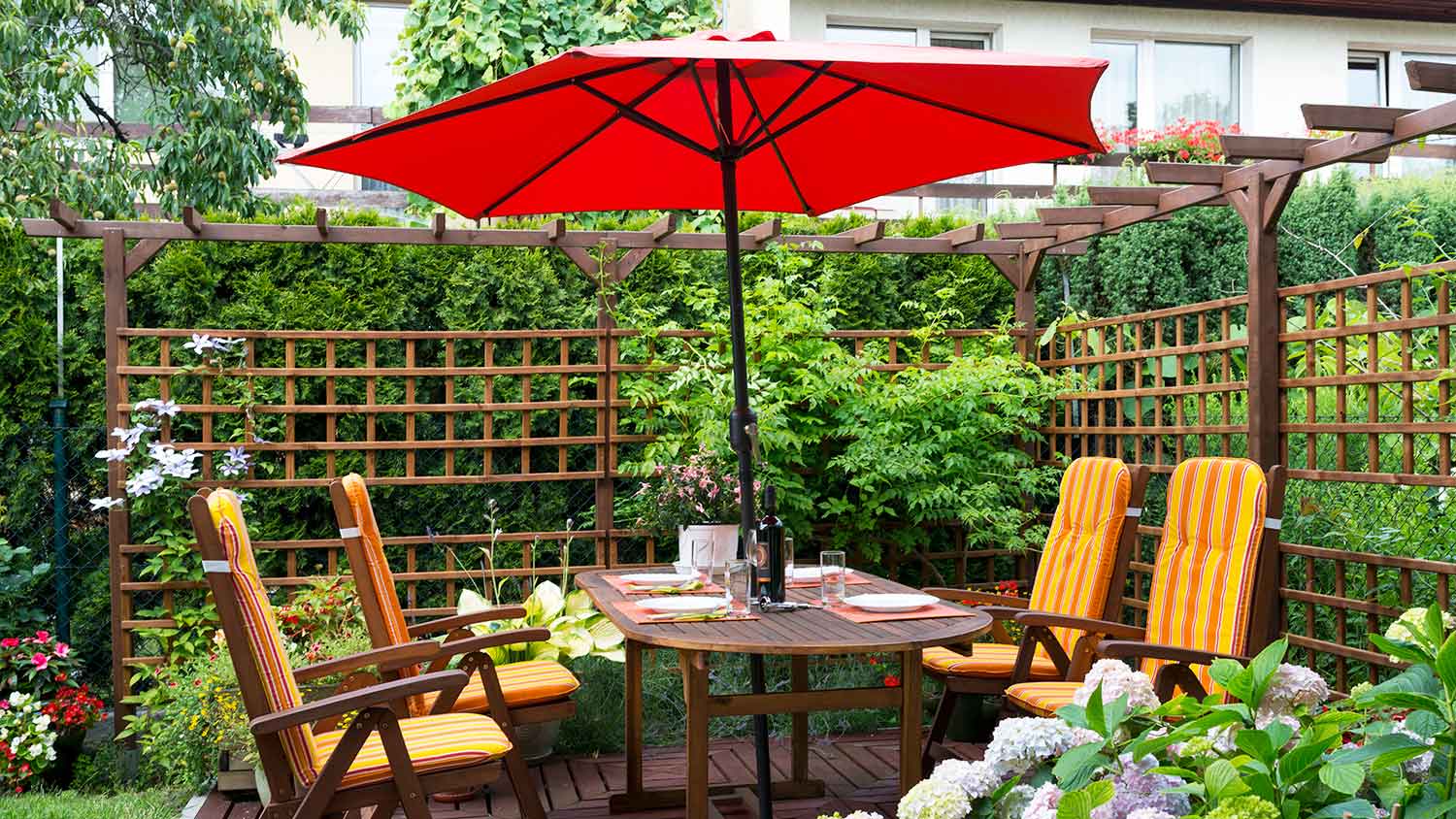 Table with red umbrella and wooden chairs on the patio