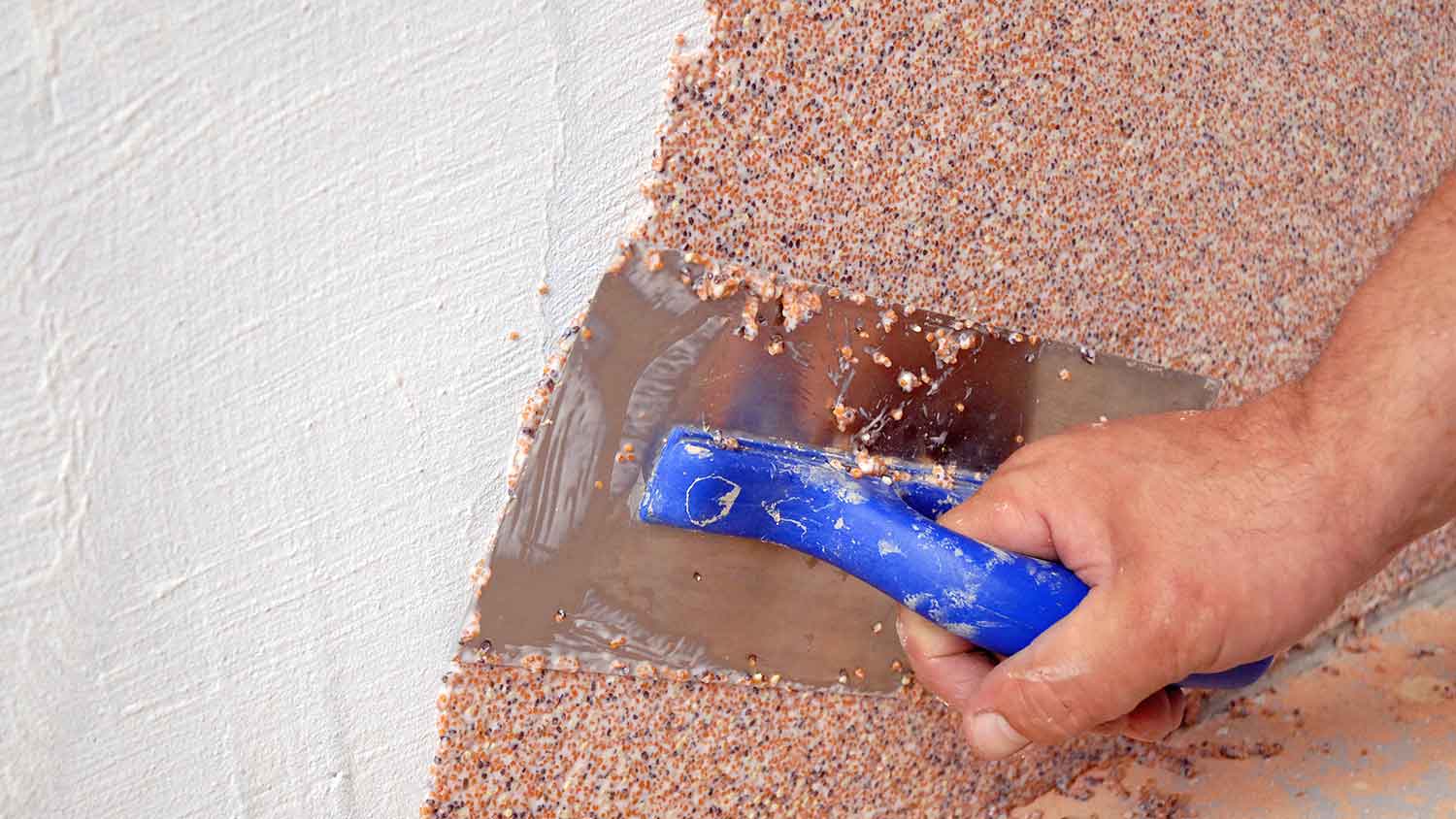 Worker applying pebbledash plaster finish