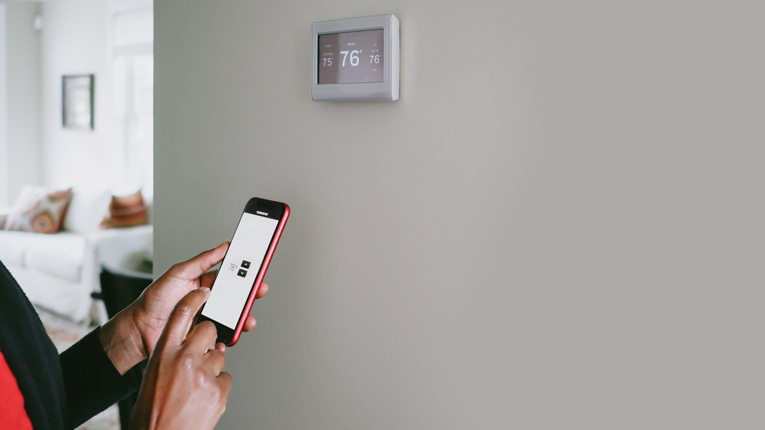 A person adjusting the room’s temperature via a smartphone