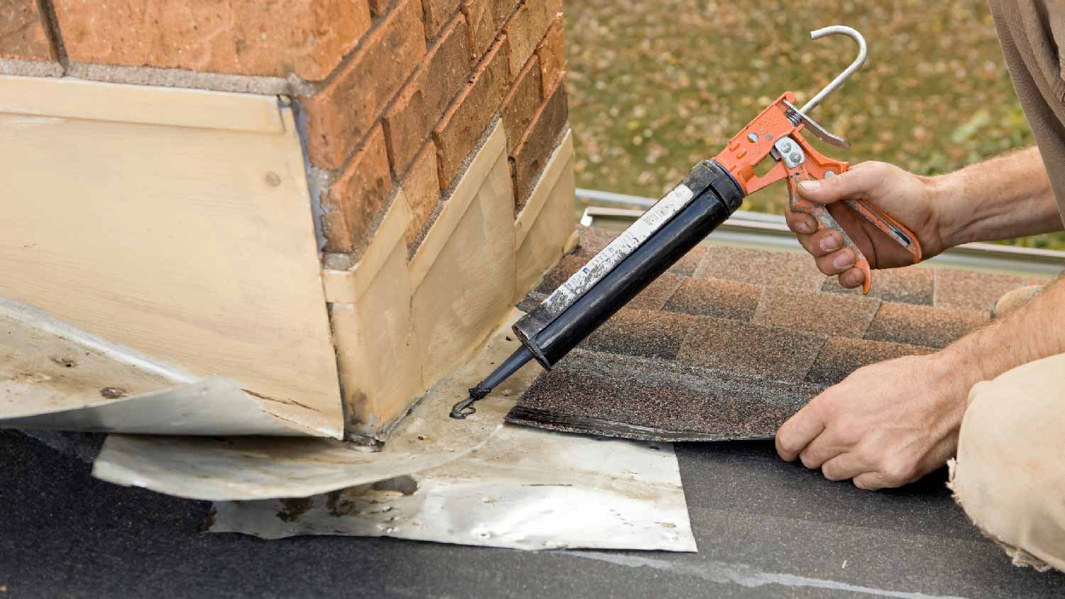 A person applying caulk on a chimney