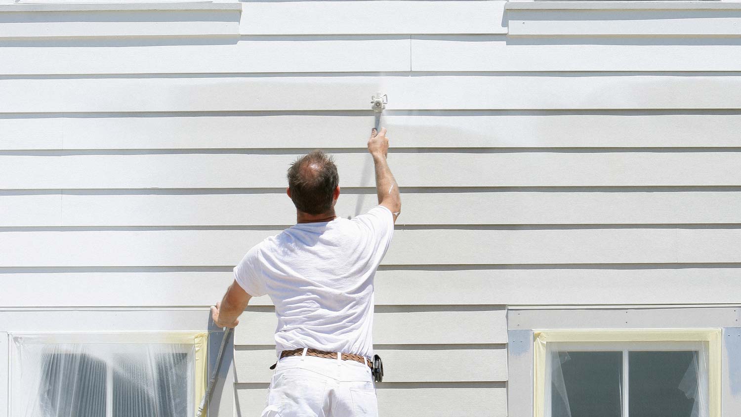 A person applying liquid siding at house