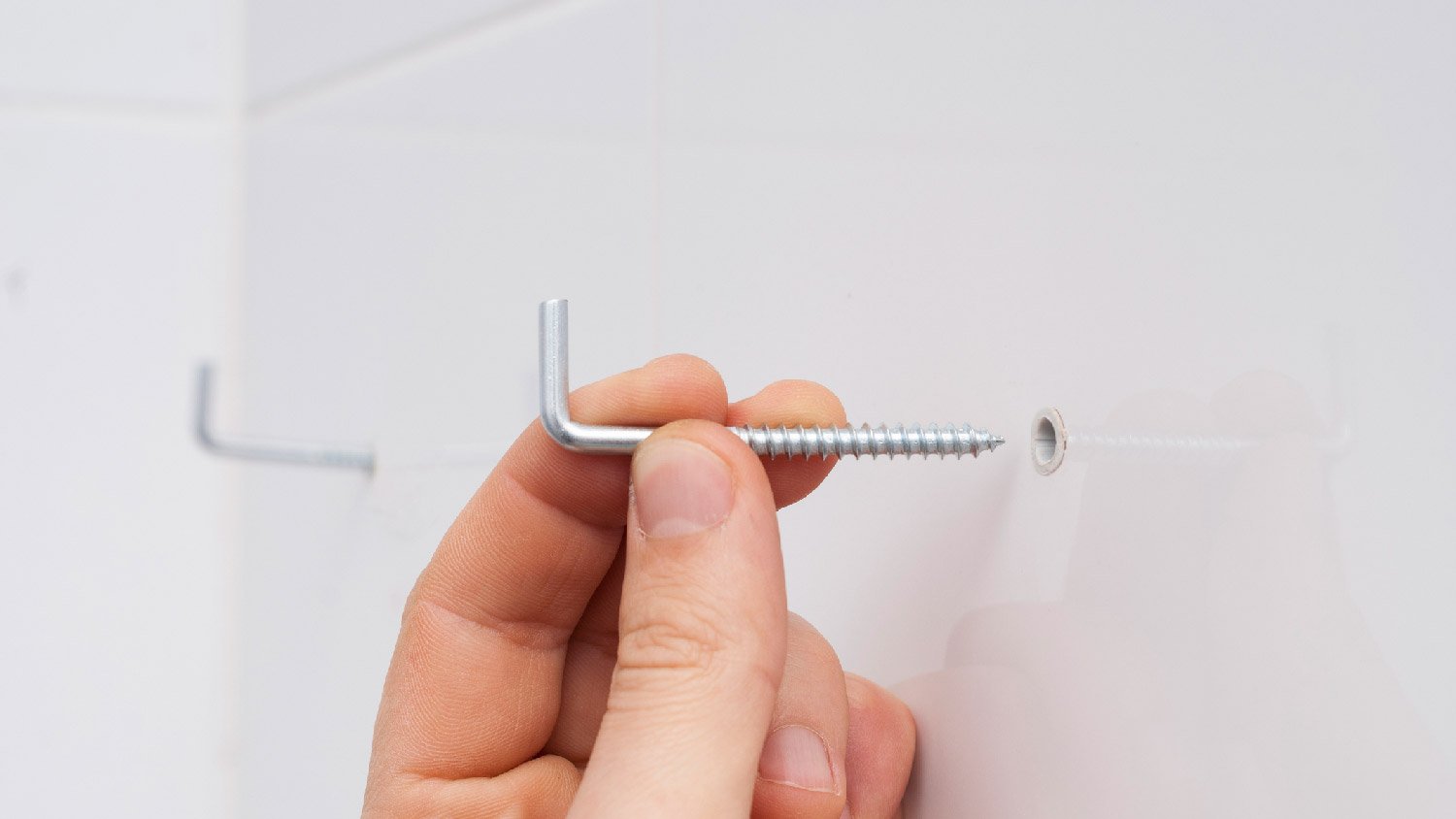 A person attaching mounting hooks to a wall