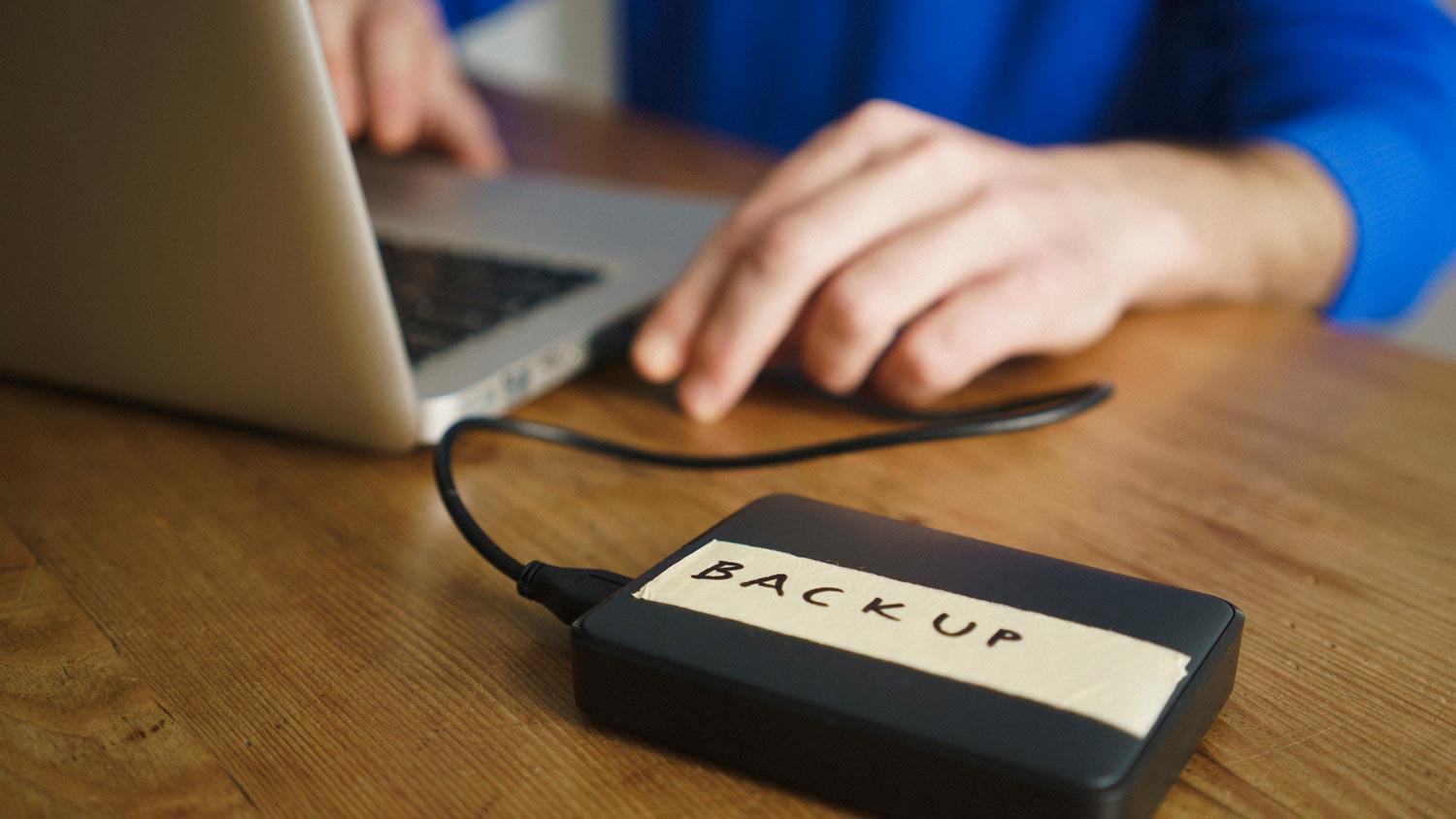 A person backing up his computer data in an external hard disk