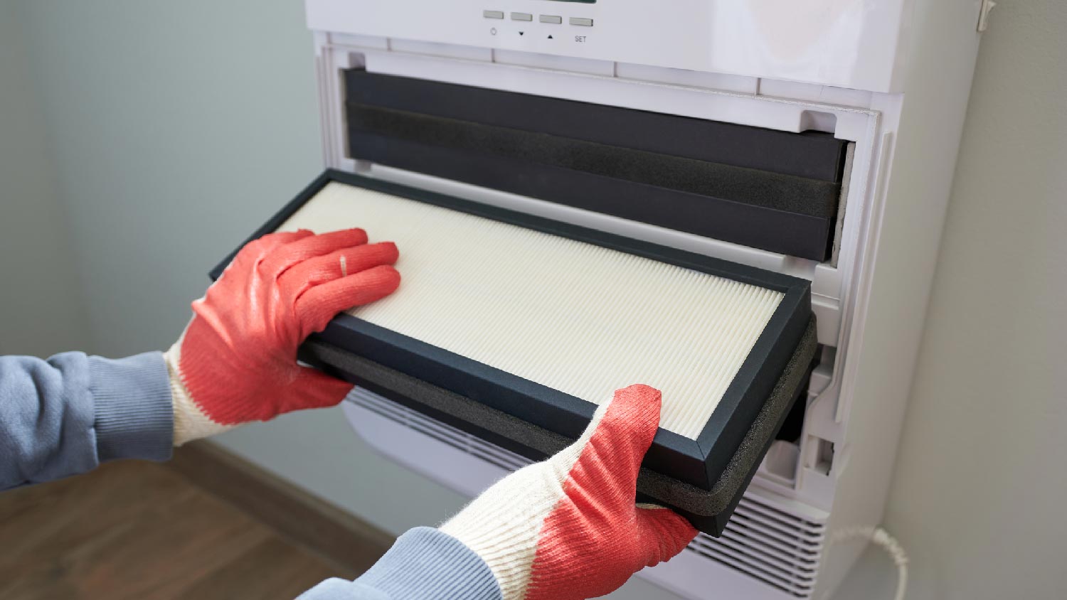 A person changing the air conditioner’s filter