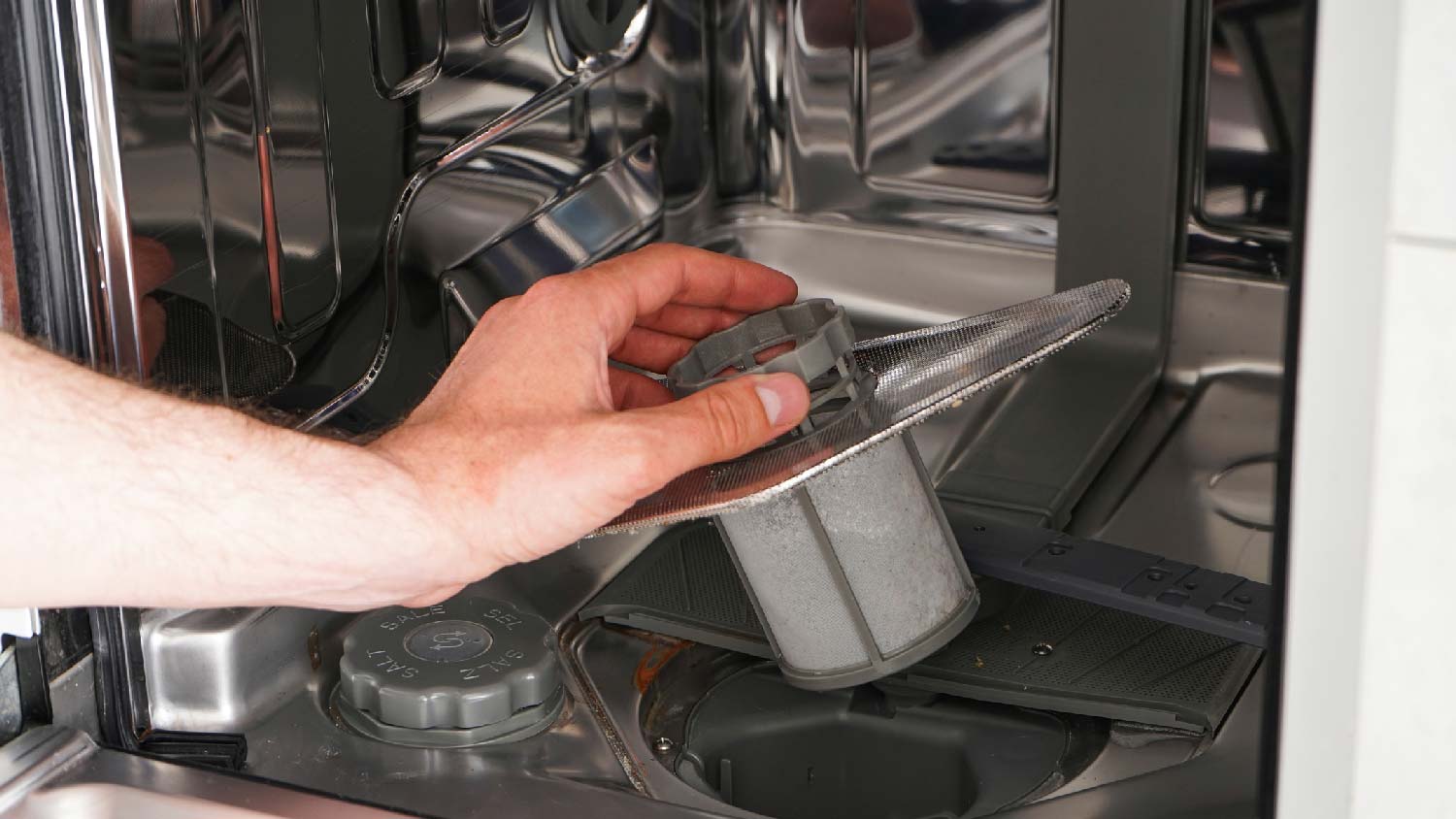 A person checking a dishwasher’s filter