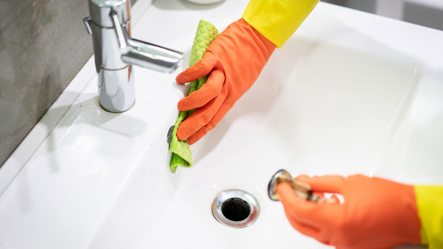 A person cleaning a bathroom sink