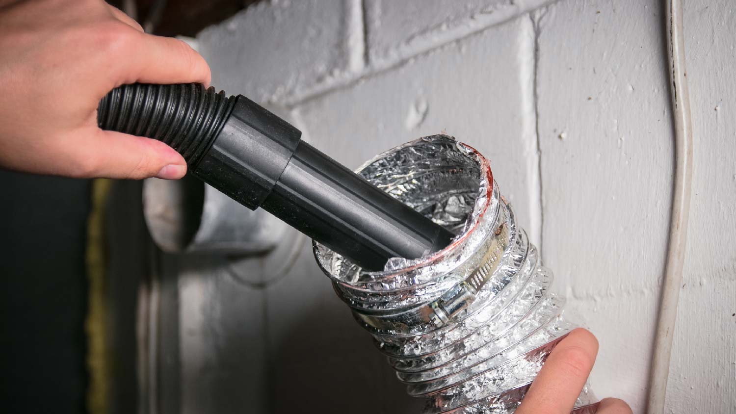 A person cleaning a dryer vent