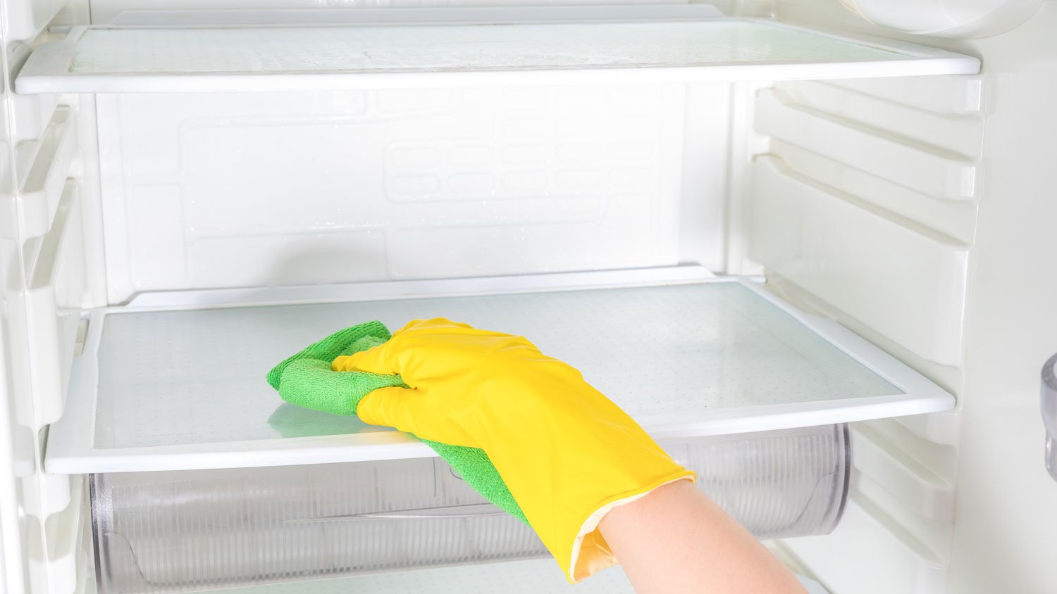 A person cleaning an empty fridge