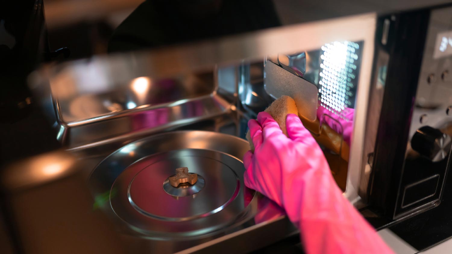 A person cleaning the inside of a microwave