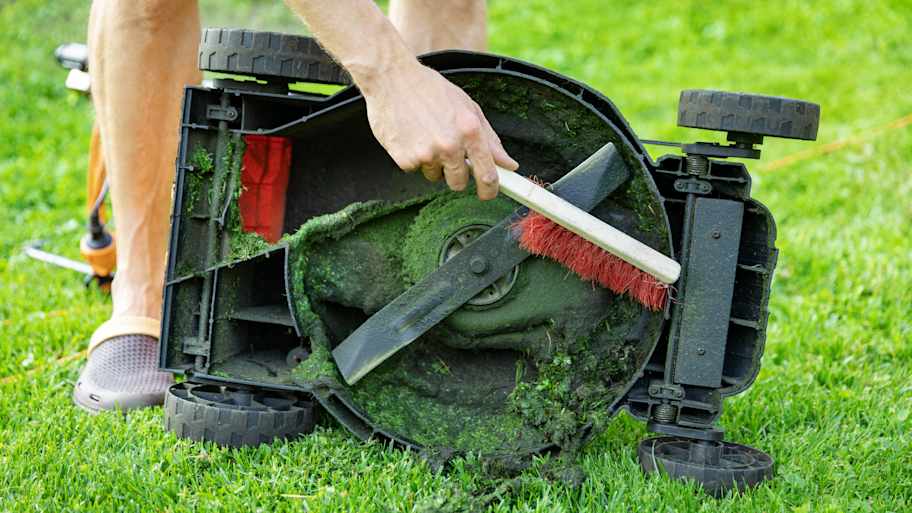 A person cleaning the lawn mower