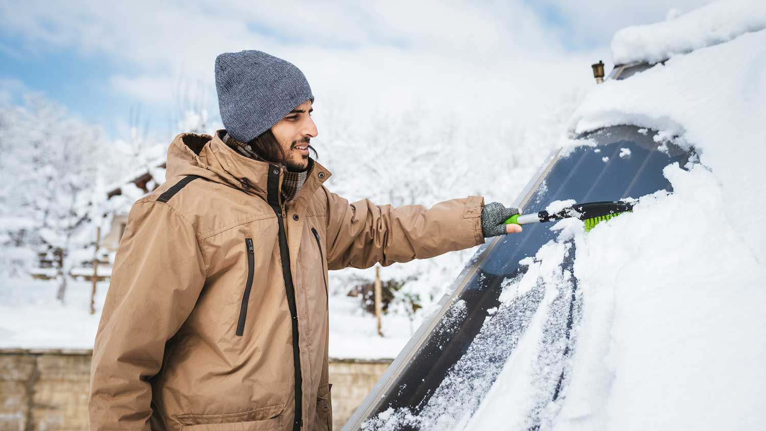 A person cleaning snow off a solar panel with a brush