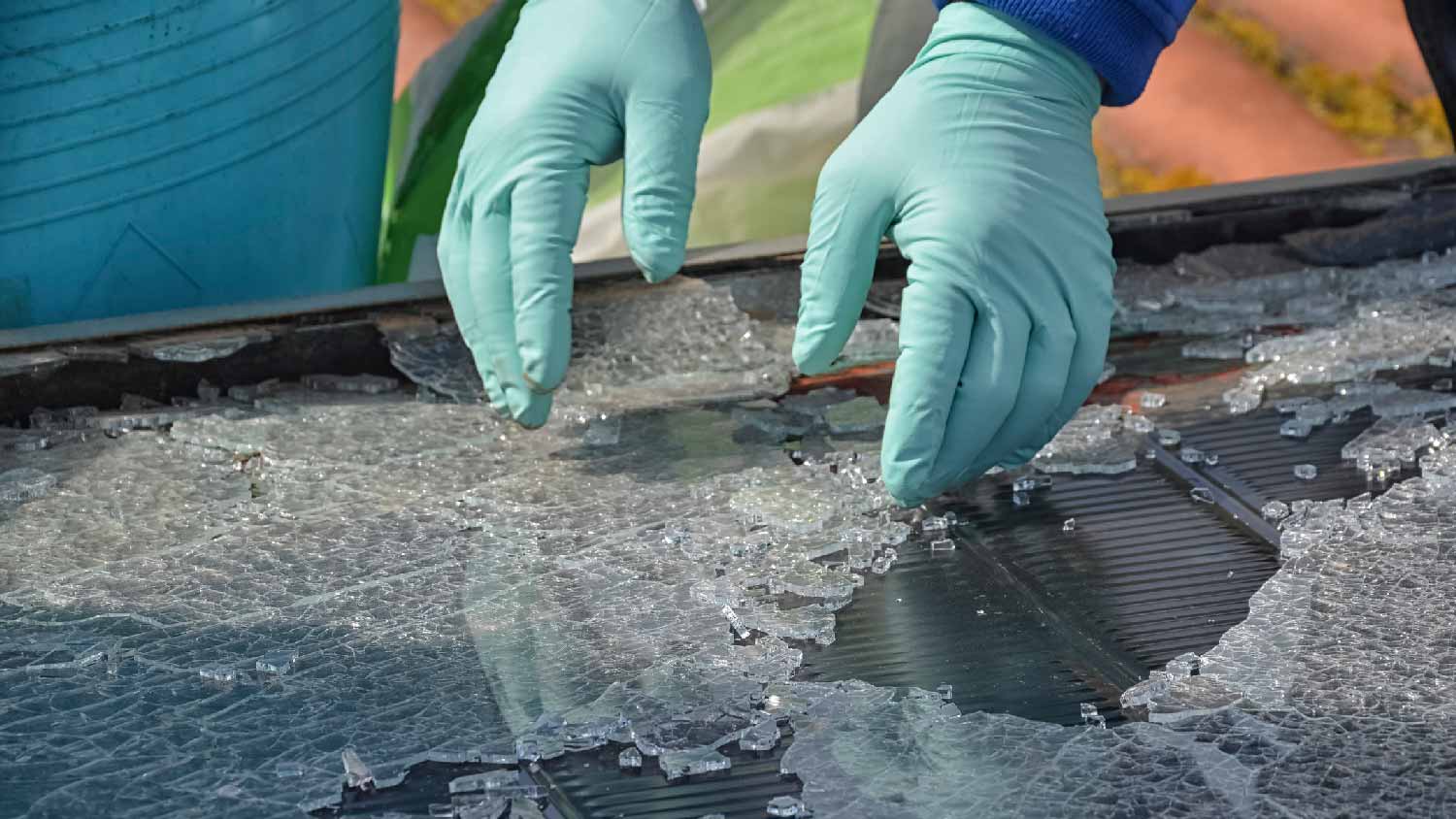 A person collecting glasses from a destroyed from hail solar panel