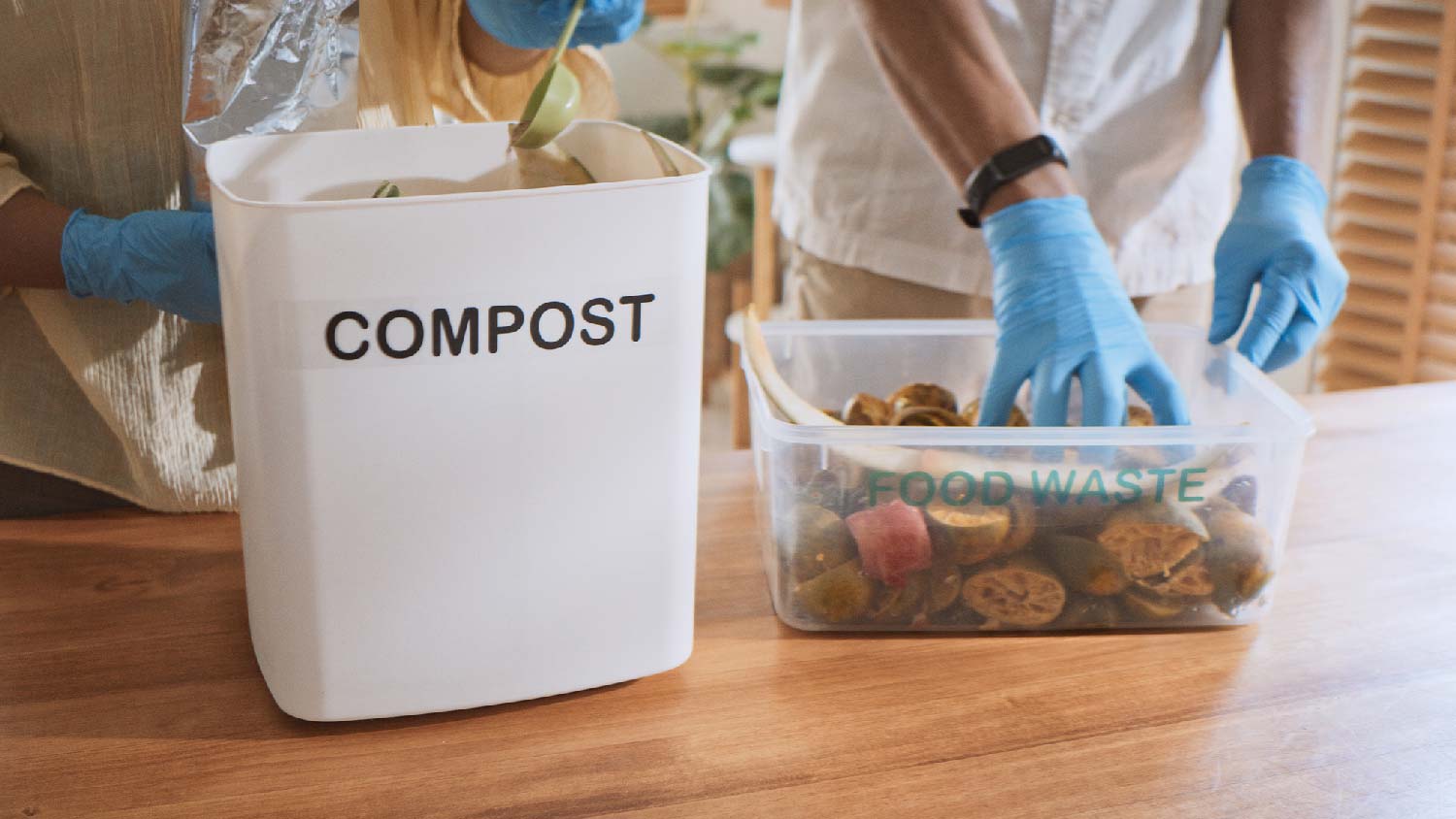 A person composting food leftovers in the kitchen