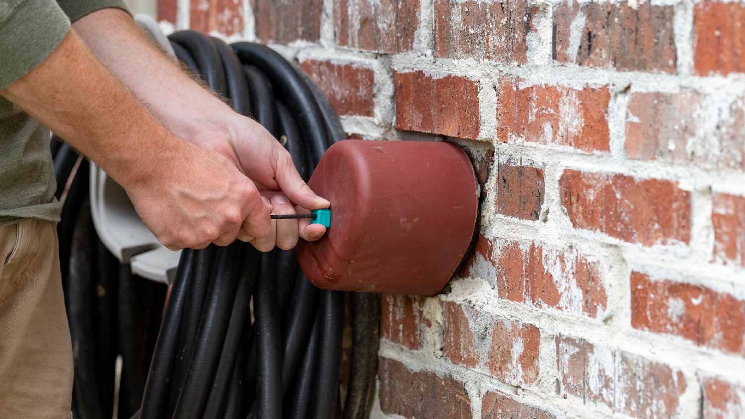 A person covering an outdoor faucet