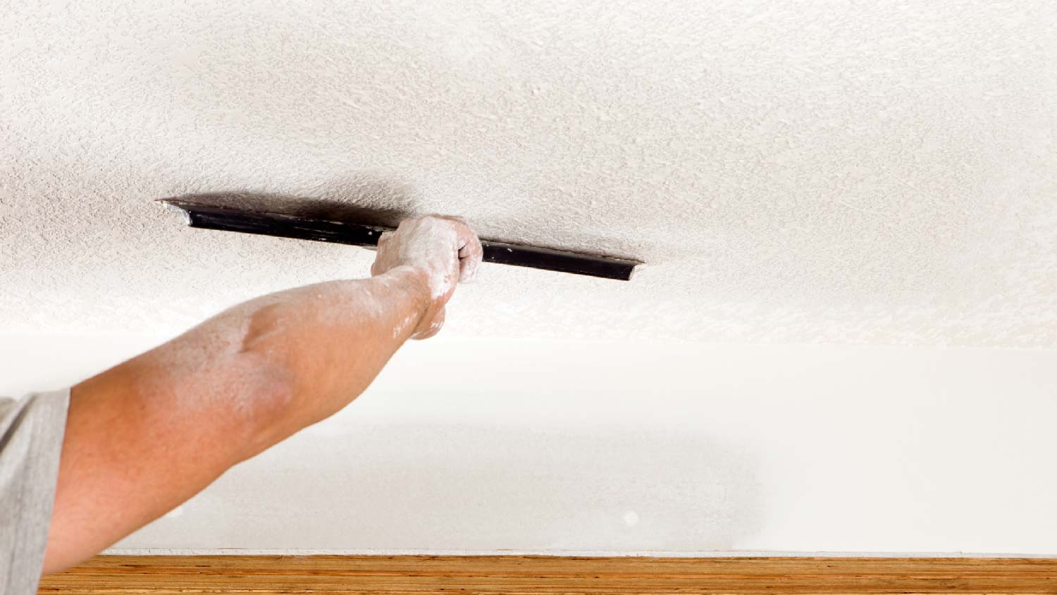 A person creating a knockdown ceiling texture