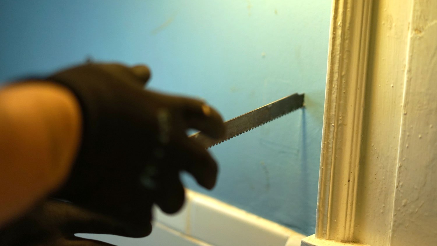 A person cutting a drywall with a jab saw 