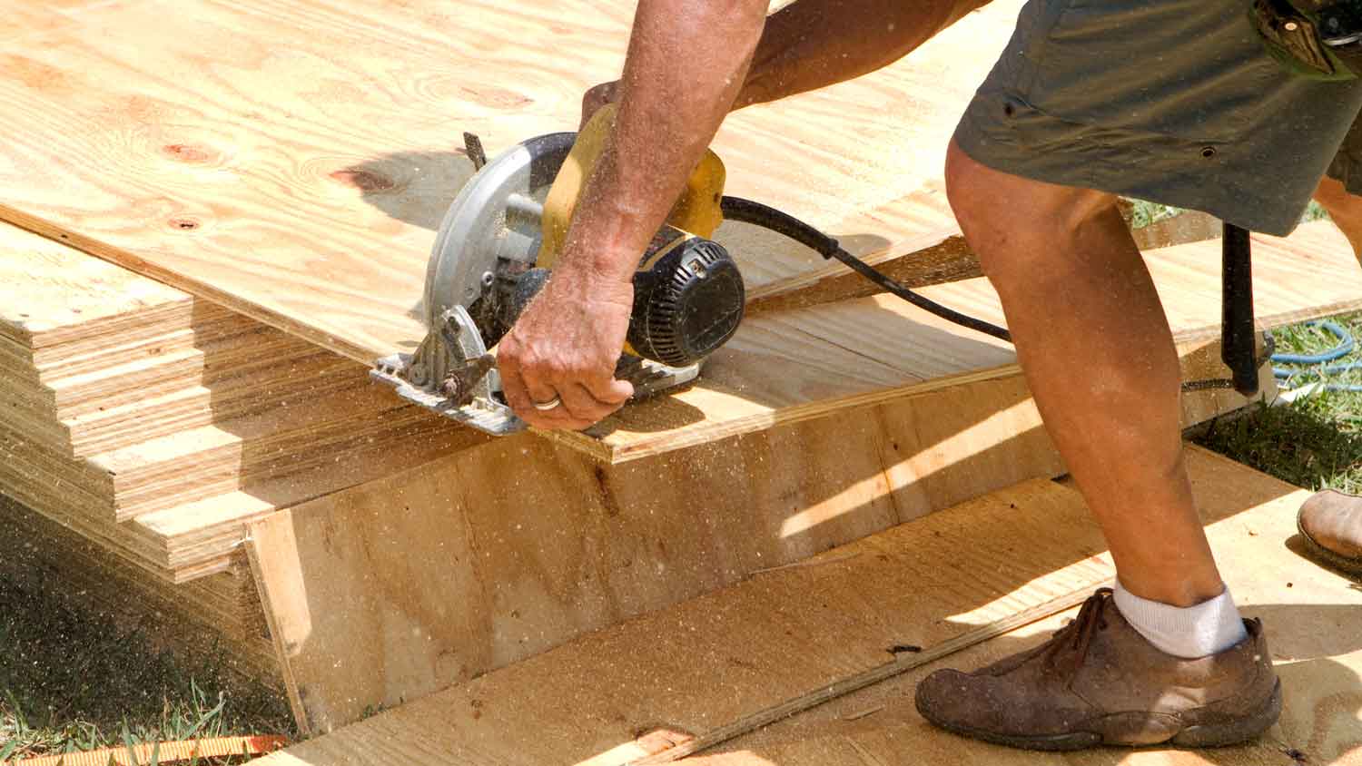 A person cutting plywood for subfloor